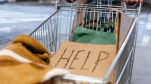 Shopping cart with cardboard sign asking for HELP.