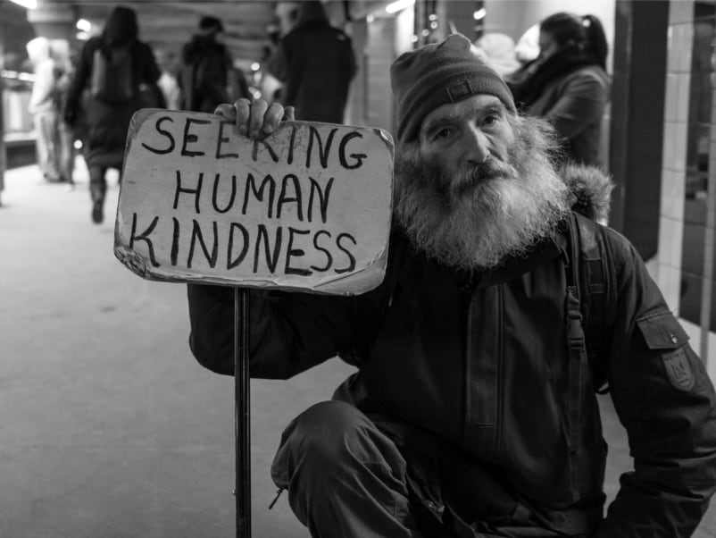 Homeless Man with sign "Seeking Human Kindness"