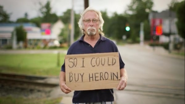 Formerly homeless man holds sign "...so I could buy heroin."